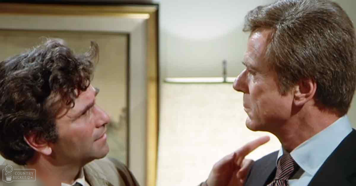 Two male adults dressed formally, one wearing a beige jacket and white shirt, the other in a dark suit with a striped tie, standing in an office environment with natural light illuminating the space.