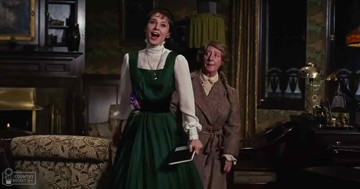 Two young adult women and an older adult woman dressed in vintage clothing indoors with ornate furniture and warm lighting.