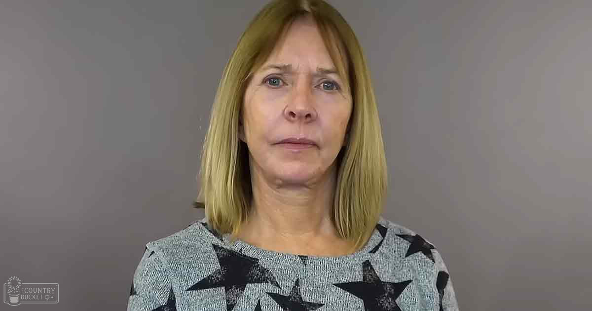 Middle-aged to older adult female wearing a light gray star-patterned sweater in a studio setting with even artificial lighting.
