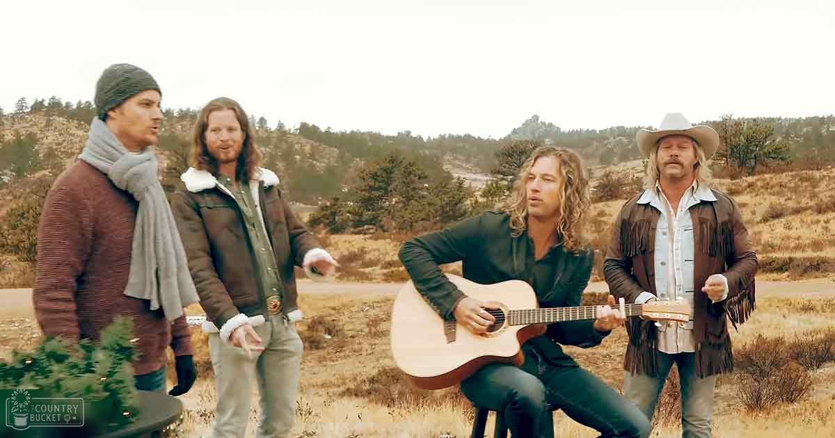 Musical performance in an outdoor rural setting with autumnal dry grass and trees; adults wearing jackets and scarves on a cloudy day.
