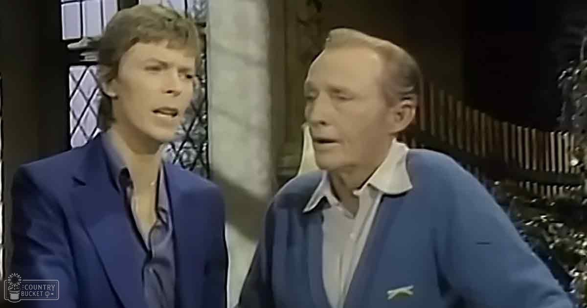 Two individuals in a mid-20th century studio setting, one wearing a dark blue blazer over a light-colored shirt and the other in a light blue cardigan over a white collared shirt.