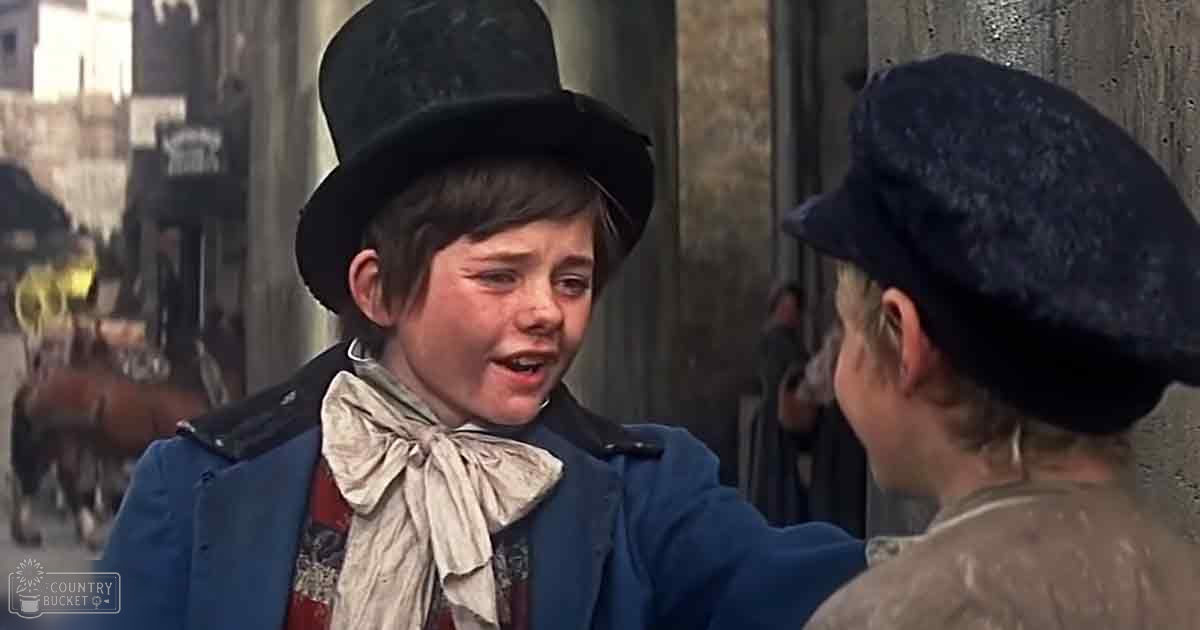 Two individuals in a bustling urban street scene of what appears to be late 19th-century London; one young boy wearing a blue jacket, white cravat, and black top hat, another adult male in a dark cap and brownish-gray coat with horse-drawn carriages visible in the background.