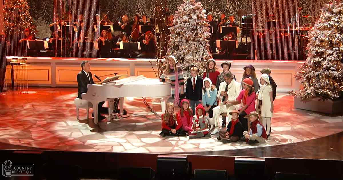 A musical performance with adults and children, Christmas-themed setting, indoor theater, evening lighting.