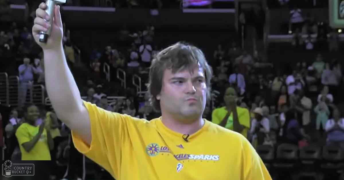 Adult male wearing a yellow 'Los Angeles Sparks' T-shirt in an indoor sports arena with spectators in casual attire during what appears to be a sporting event.