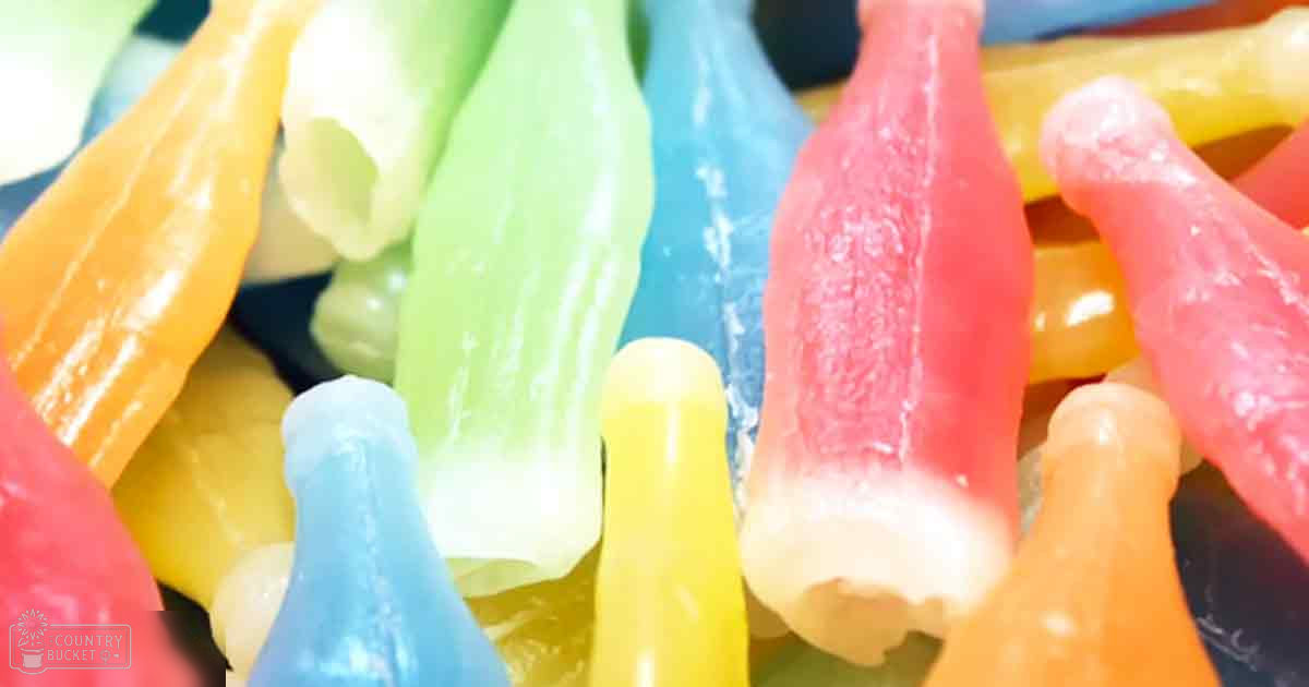Colorful bottle-shaped gummy candies displayed in a vibrant indoor setting with soft lighting.