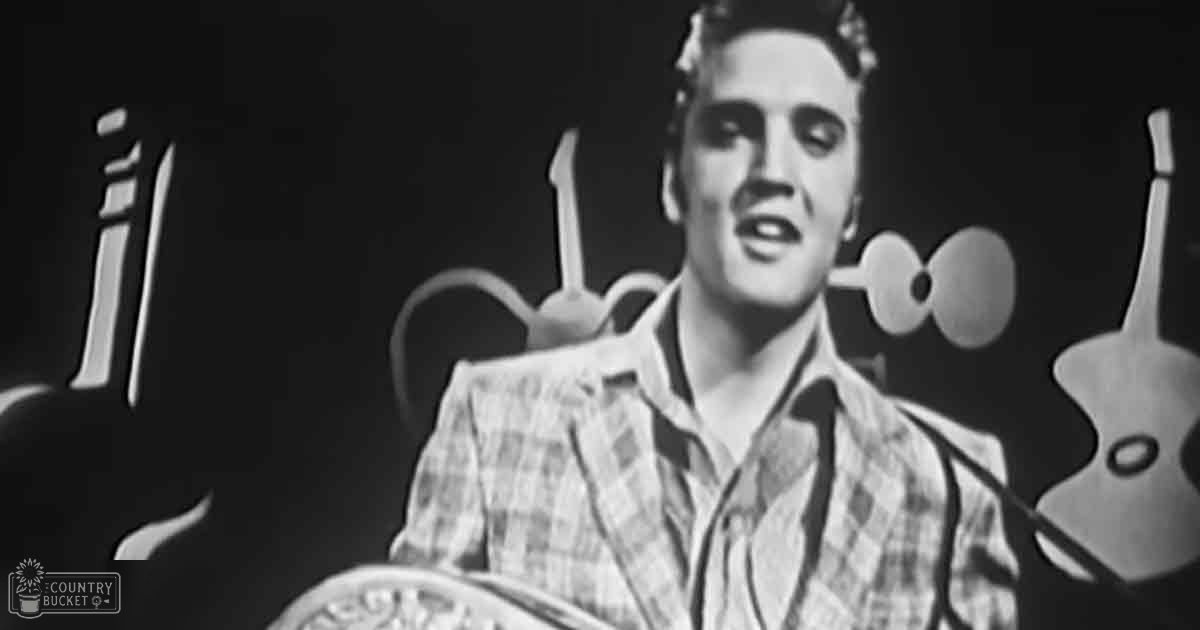 A young adult male stands in a recording studio, wearing a relaxed fit plaid shirt with long sleeves and a button-down collar.
