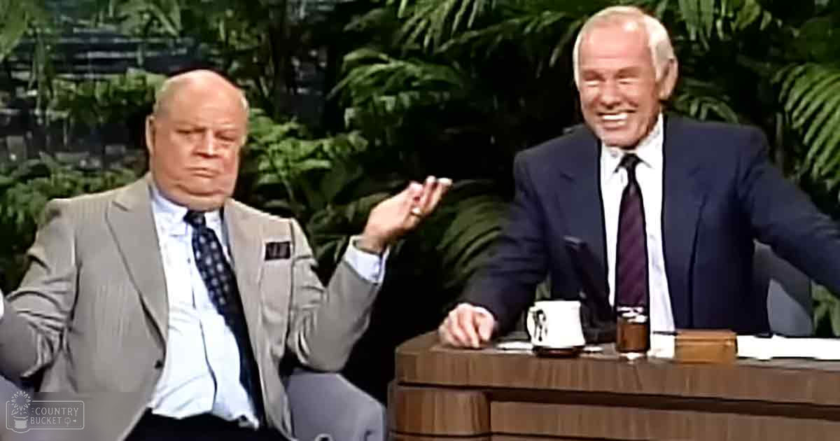 Two older adult men in formal suits at a wooden desk with lush green foliage in an indoor studio setting, likely from a mid-20th century talk show.