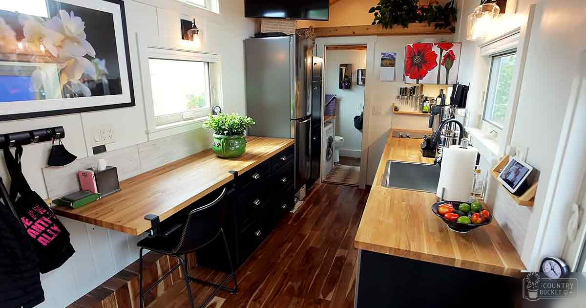 A kitchen interior with wooden countertops, a sink area with fruits, and various kitchen tools on a wall-mounted shelf.