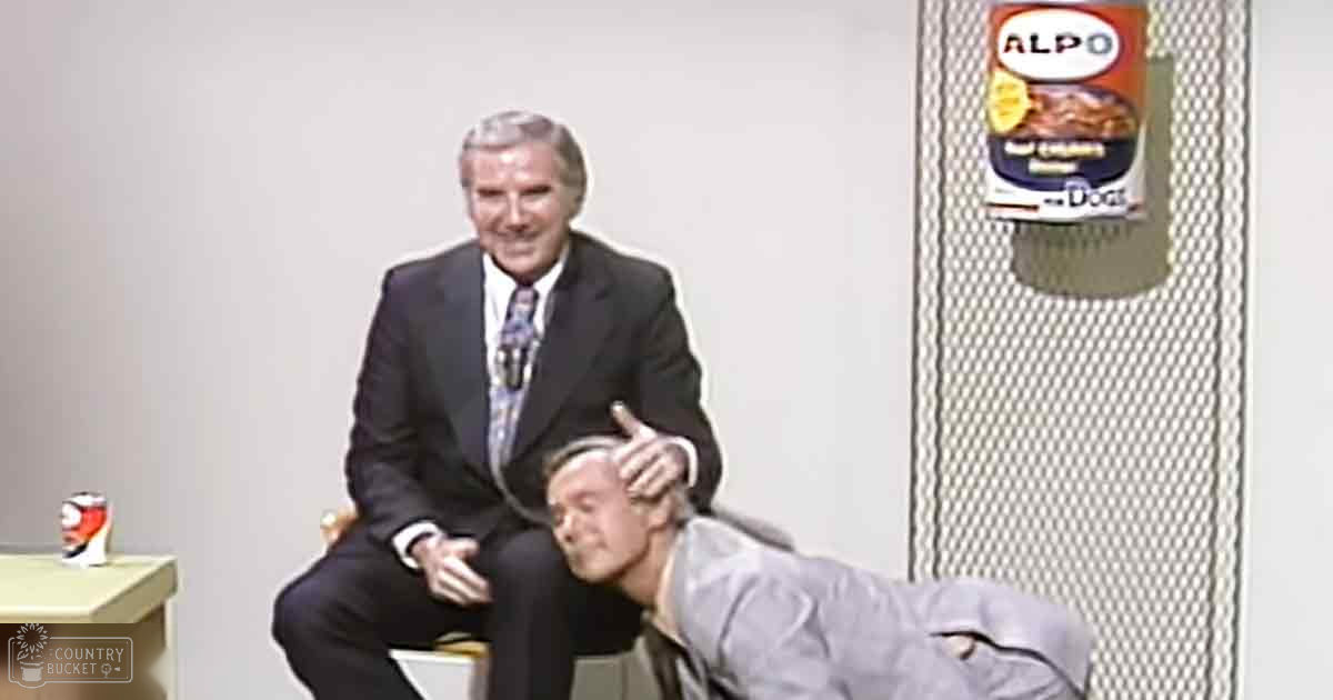 Older adult male in dark suit, seated with younger male in casual shirt; indoor studio setup with 'ALPO' dog food poster visible.