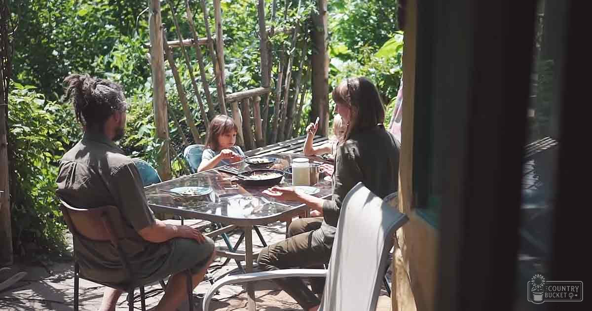 A family dining outdoors surrounded by lush greenery on a bright, sunny day.