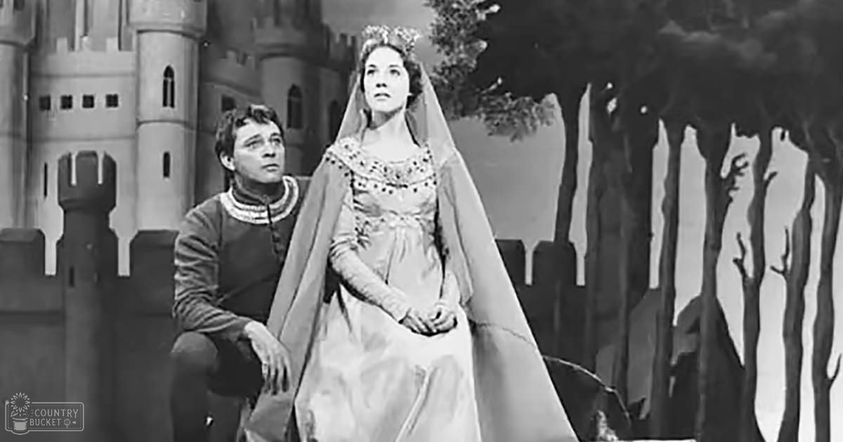 Theatrical scene with a castle backdrop with an adult male singer in a dark tunic and a female figure in a flowing gown, set against bare trees suggesting late autumn or winter.