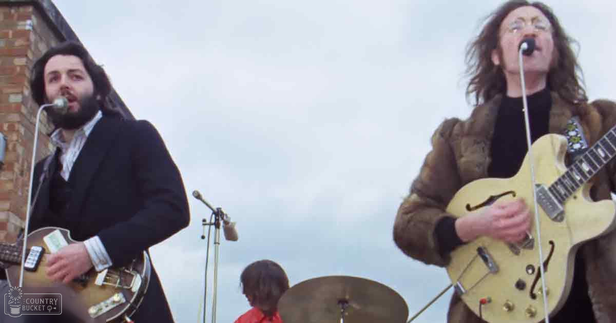 Musical performance with two adult male musicians in black and brown jackets, an adult male child wearing red, outdoors under overcast sky.