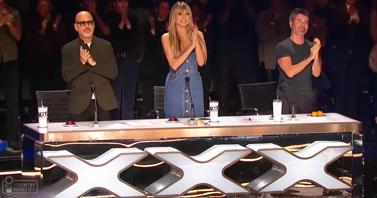 A talent show judging panel scene with three judges, an older adult male in a suit, a young female judge in denim, and a middle-aged man clapping. The setting is indoors with artificial lighting typical for television productions.