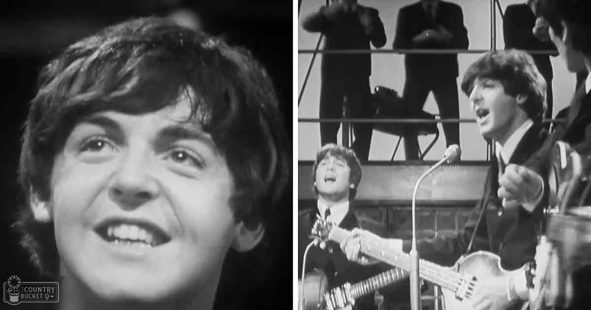 A young adult male singer dressed in a dark suit, performing with a group of similarly dressed individuals in a studio setting.