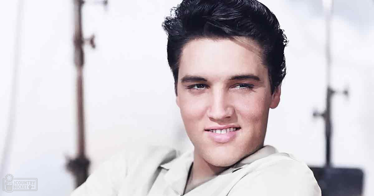 Young adult male wearing a beige, collared, long-sleeved open-front shirt in an indoor photo studio setting with soft artificial lighting.