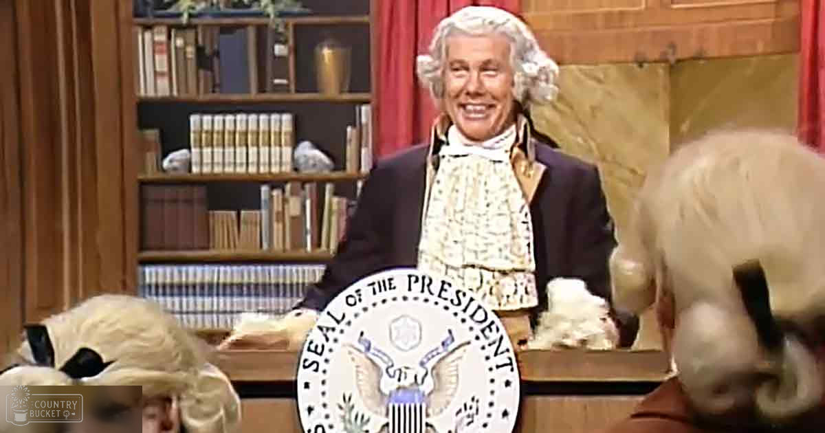 An older adult male in a colonial-style suit, resembling George Washington, stands in an office-like studio setting with wooden paneling and red curtains. A dog in costume, possibly a wolf breed, wears a muzzle and accessories nearby.
