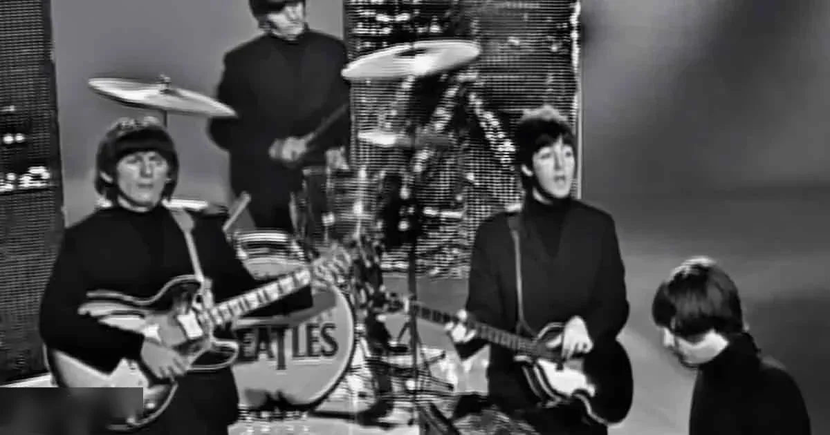 The Beatles performing in a studio setting with musical instruments and controlled lighting.