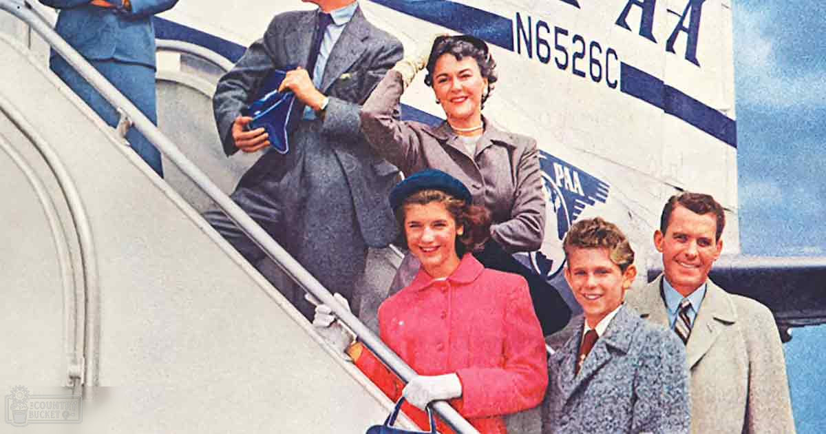 A family disembarks from a Pan Am Airlines plane at an airport during the daytime, with clear skies suggesting spring or summer.
