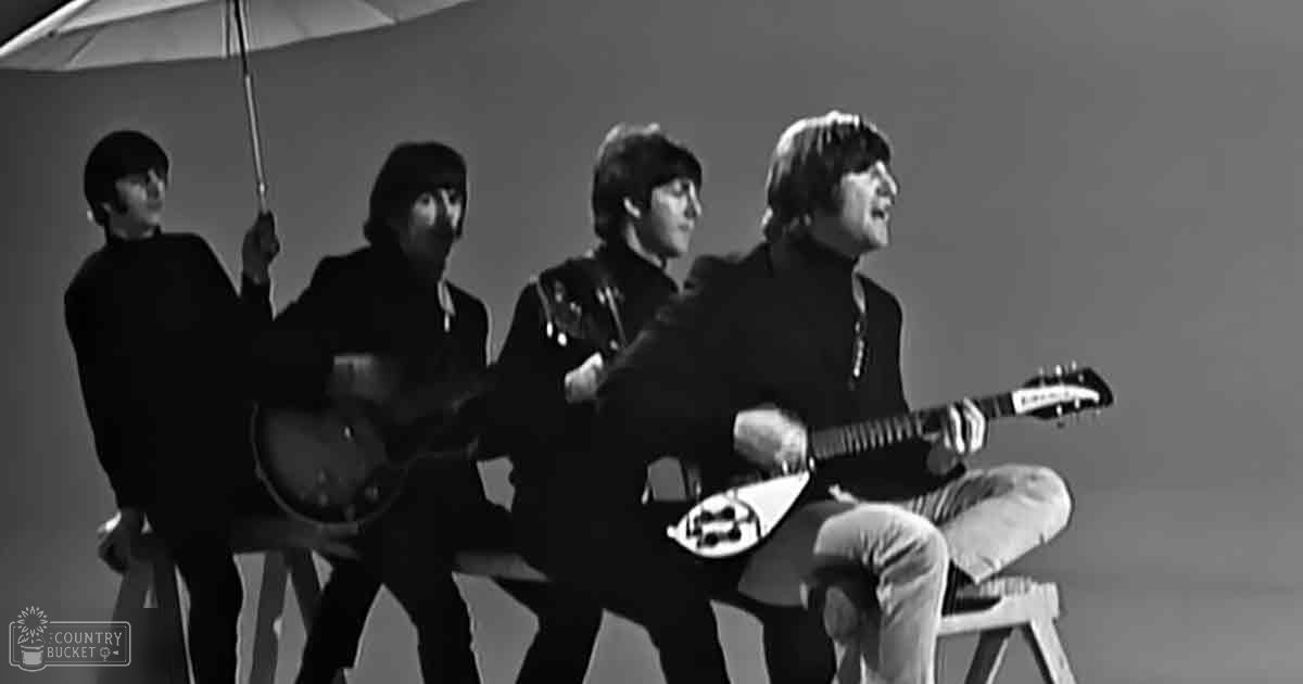 A musical group in a studio setting, dressed uniformly in dark-colored jackets from the 1960s era.