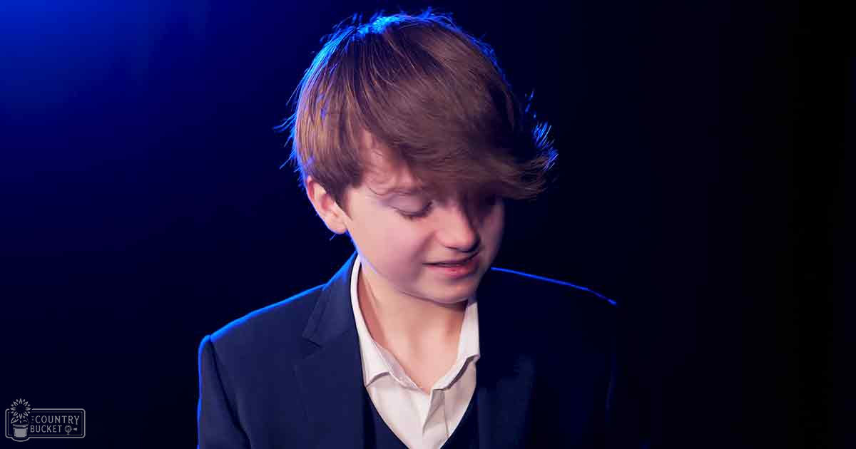 A young boy in an indoor setting, wearing a dark blue blazer and light-colored shirt.