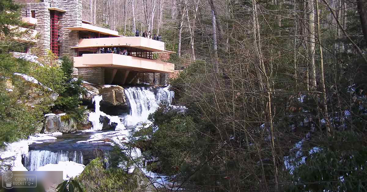 Fallingwater, Pennsylvania; adults in wool-like jackets amidst a waterfall and dense forest, late fall or winter day;