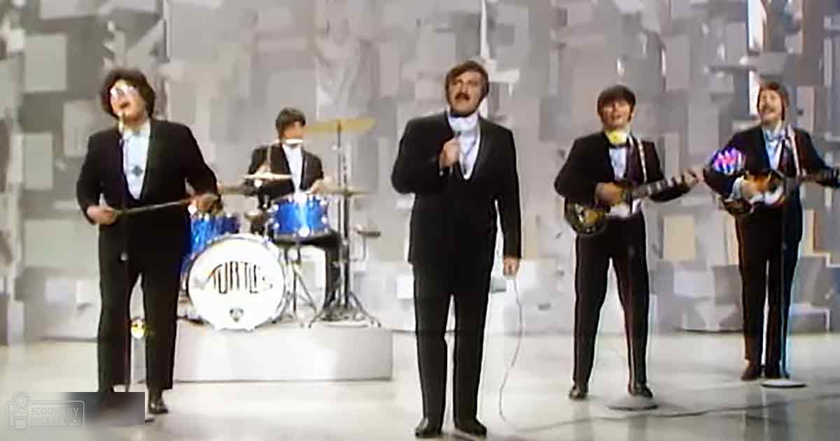 Musical performance group in an indoor studio setting, with tambourine, drums labeled 'Turtles', electric guitar, and banjo against a stylized urban backdrop with muted tones.