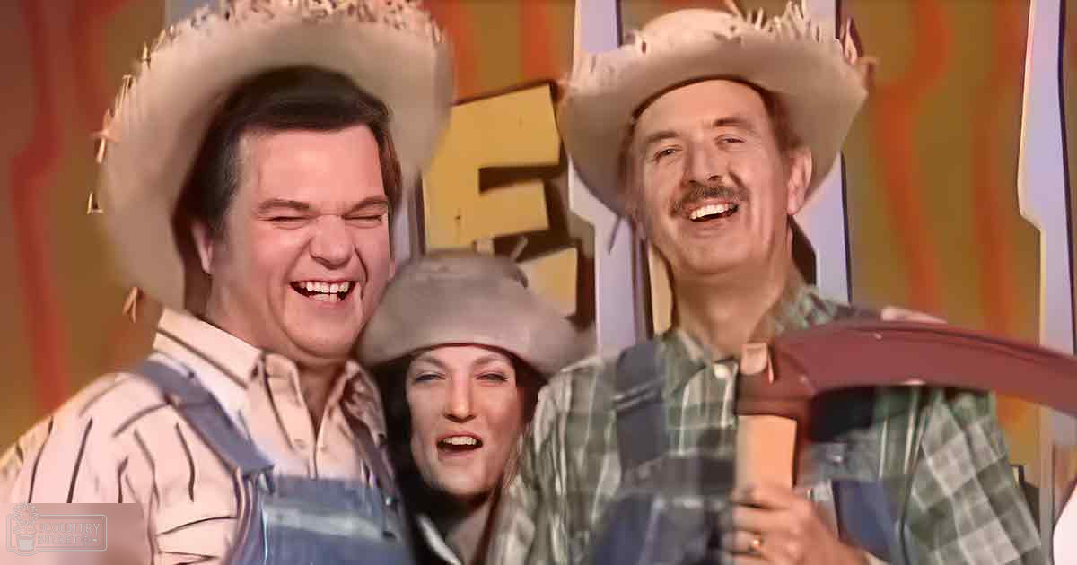 A comedic performance scene indoors with bold orange and yellow tones in the backdrop suggesting a themed set design.