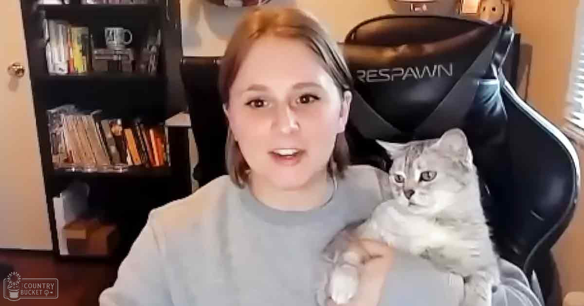 Young adult female in a casual indoor setting, interacting with an adult gray tabby cat; black gaming chair labeled 'RESPAWN' and bookshelf filled with books and items visible.