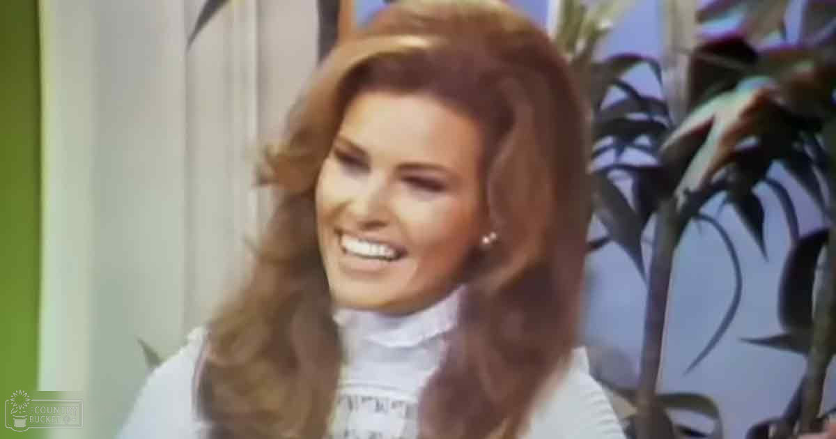 Young adult female wearing a relaxed white blouse with long sleeves and high collar indoors, accessorized with pearl earrings.