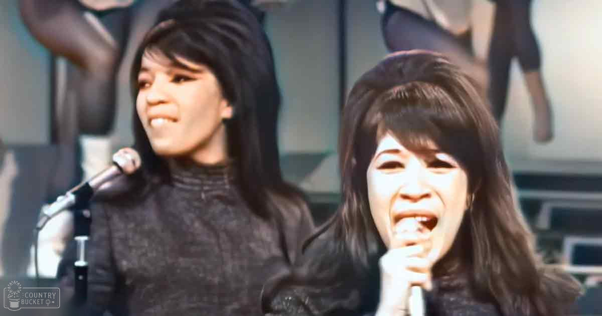 Young adult female performers wearing textured sweaters, possibly from the late 1960s to early 1970s, performing on stage with a microphone and abstract backdrop.