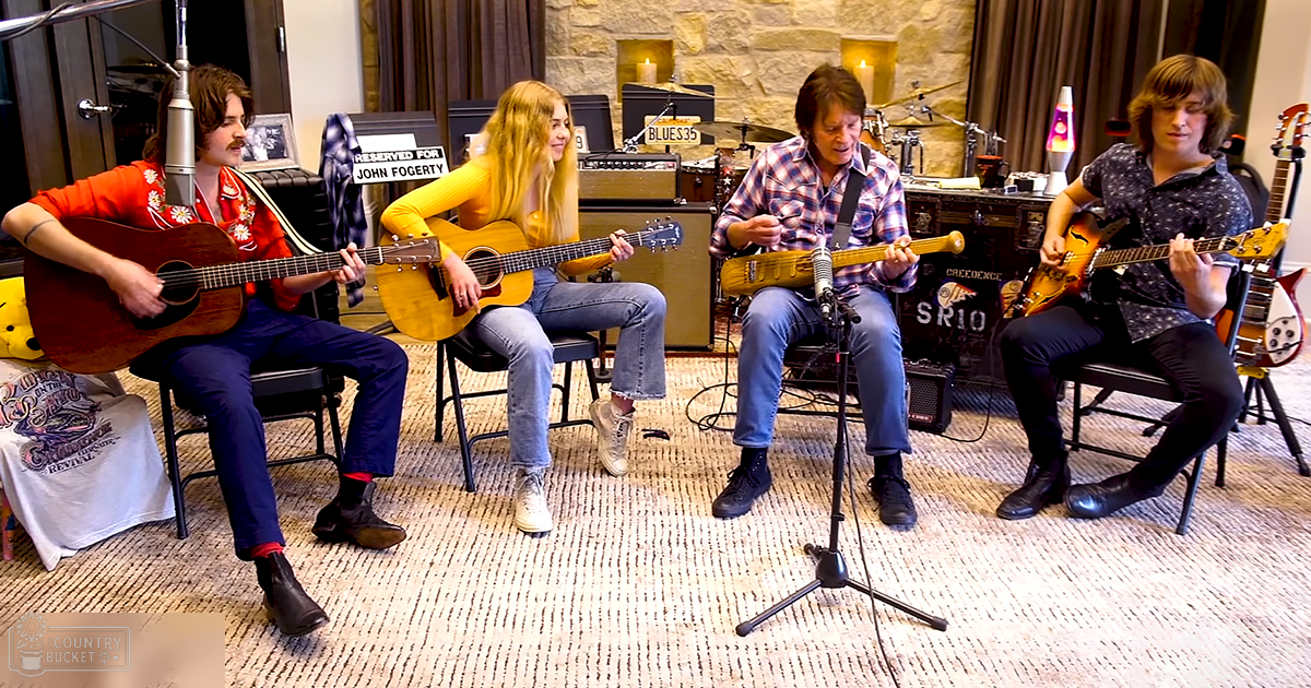 Musical performance in an indoor studio with musical instruments, controlled lighting, and stone walls; adults wearing patterned shirts, jeans, and sneakers.