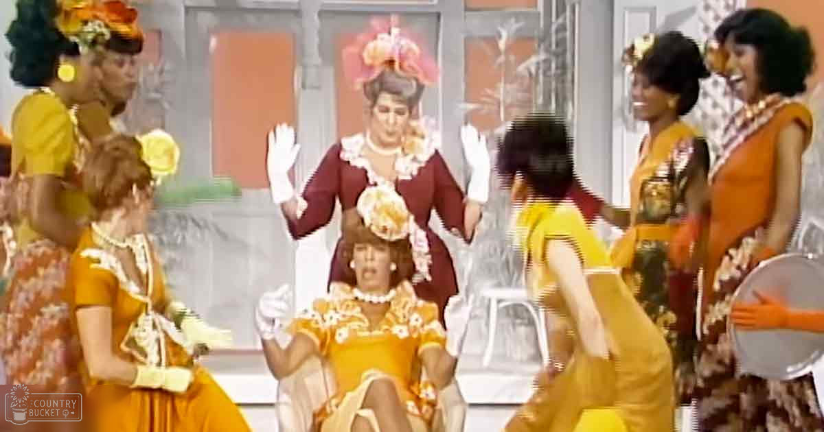 A performance scene with young adult females wearing vintage-style dresses and pearl accessories, set against a backdrop of simple props suggesting a tropical theme.