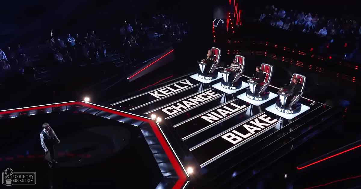 A stage setup from 'The Voice,' likely during an audition round, with judges' chairs visible.