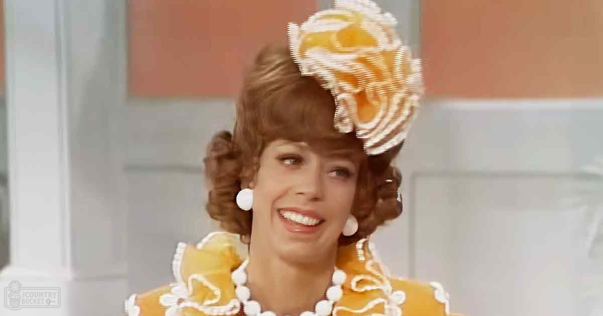 An adult female in a yellow dress with white lace trim, possibly from the 1960s or 70s, indoors with light-colored walls and natural daylight.