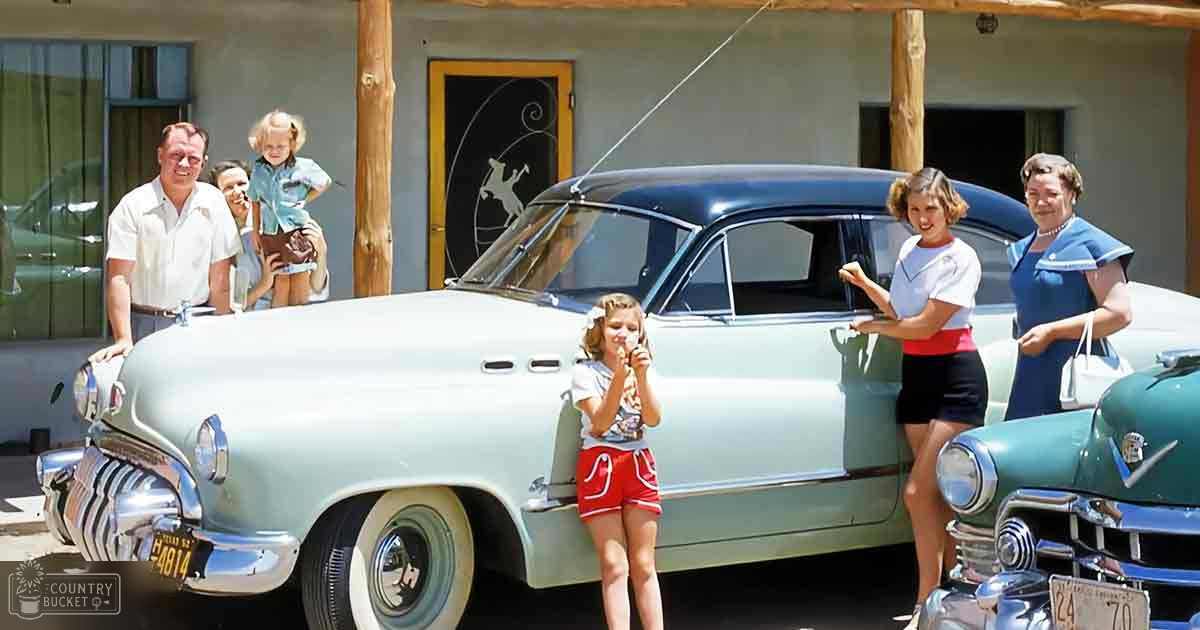 A family of four stands in front of a vintage car, likely in Texas, during what appears to be summer. The scene includes wooden beams and decorative elements in the background.