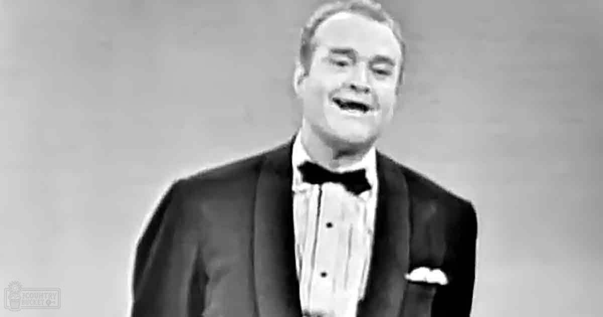 A middle-aged adult male in a classic tuxedo with a bow tie, set against a plain light-colored indoor background, likely from a mid-20th century studio environment.