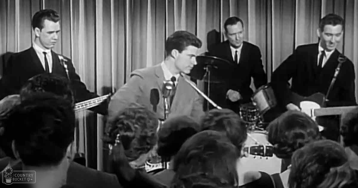 A musical performance with young adults as band members and audience in an indoor venue at night.