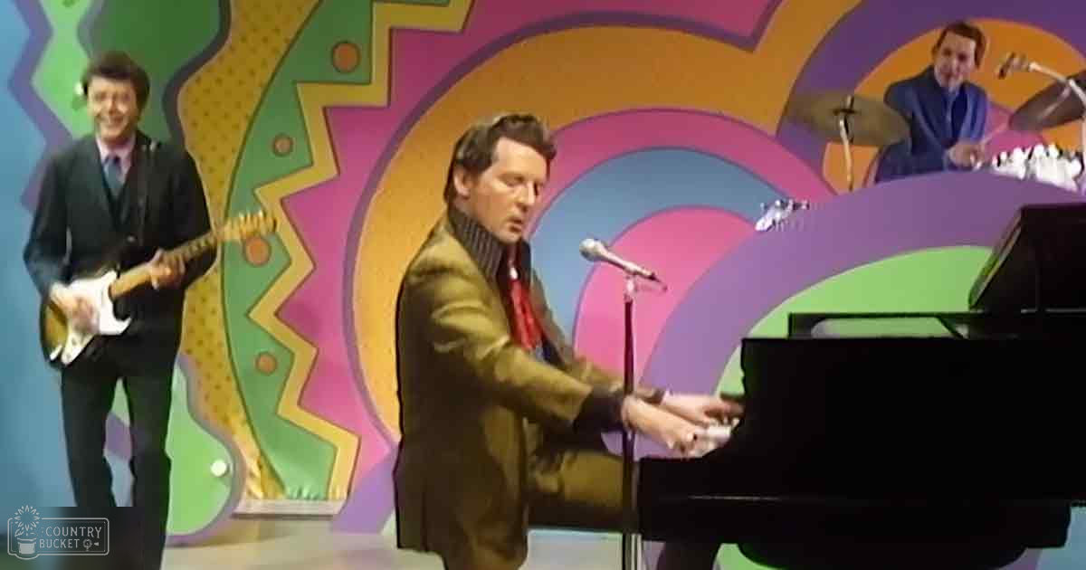 Adult male performers playing piano on a vibrant indoor stage with colorful abstract patterns and bright colors like green, pink, purple, yellow, orange, and brown in the backdrop.