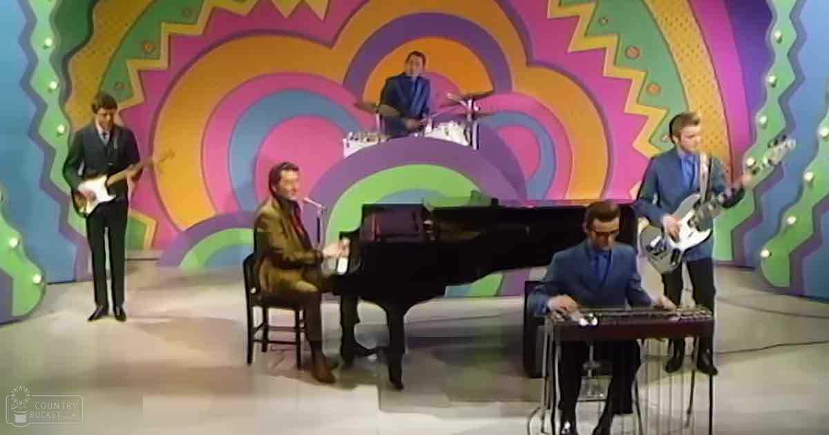 A vibrant indoor stage scene with five young adult males performing music, surrounded by colorful psychedelic backdrops and musical instruments.