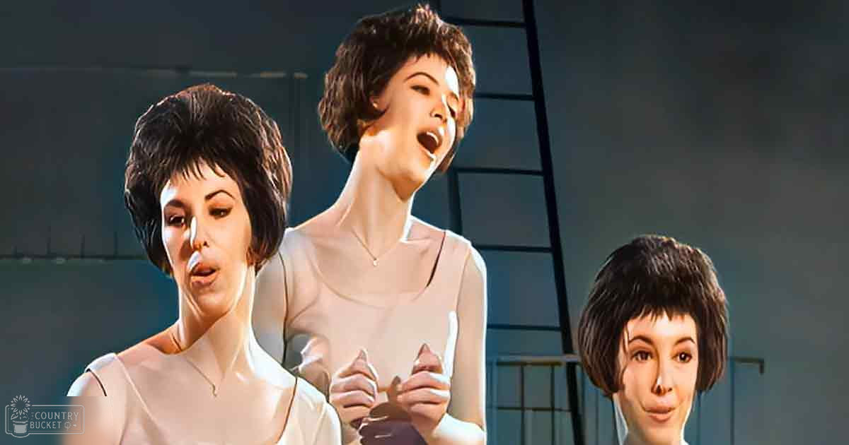 Three young adult female performers in a musical stage setting, wearing white and pale pink sleeveless tops with smooth fabric and visible necklaces.