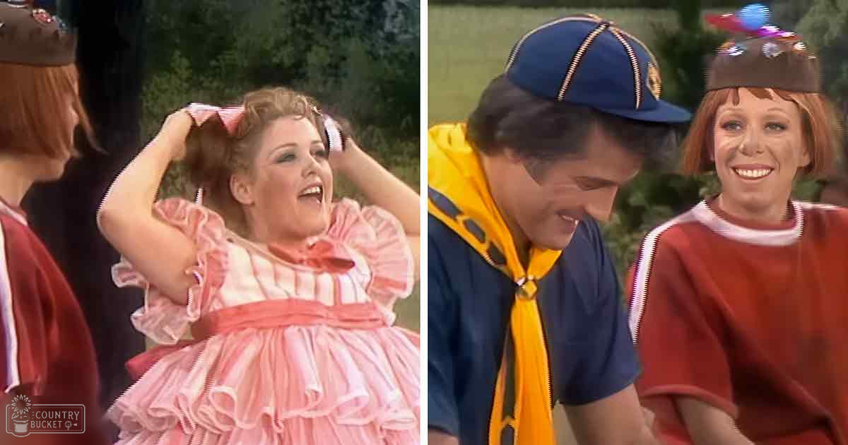 A toddler in a frilly pink dress with ruffled sleeves and a white headband stands outdoors, accompanied by two adults wearing casual clothing; the scene suggests spring or summer with lush greenery.
