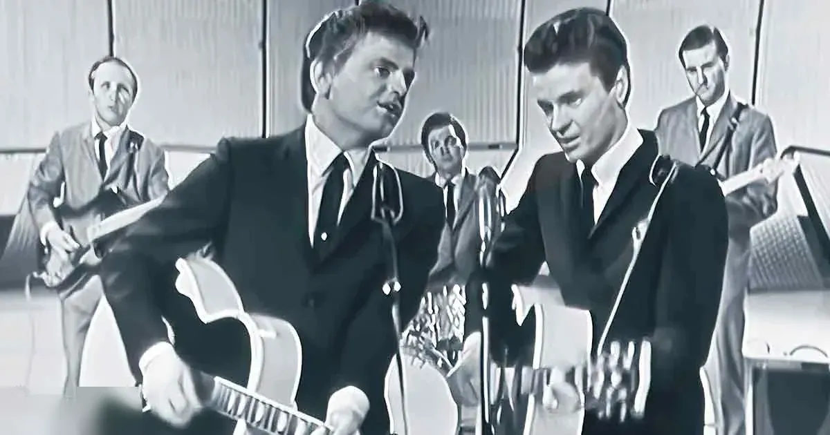 A mid-20th century musical performance scene with young adult male singers in formal suits against a simple indoor backdrop, possibly a studio or stage setting.