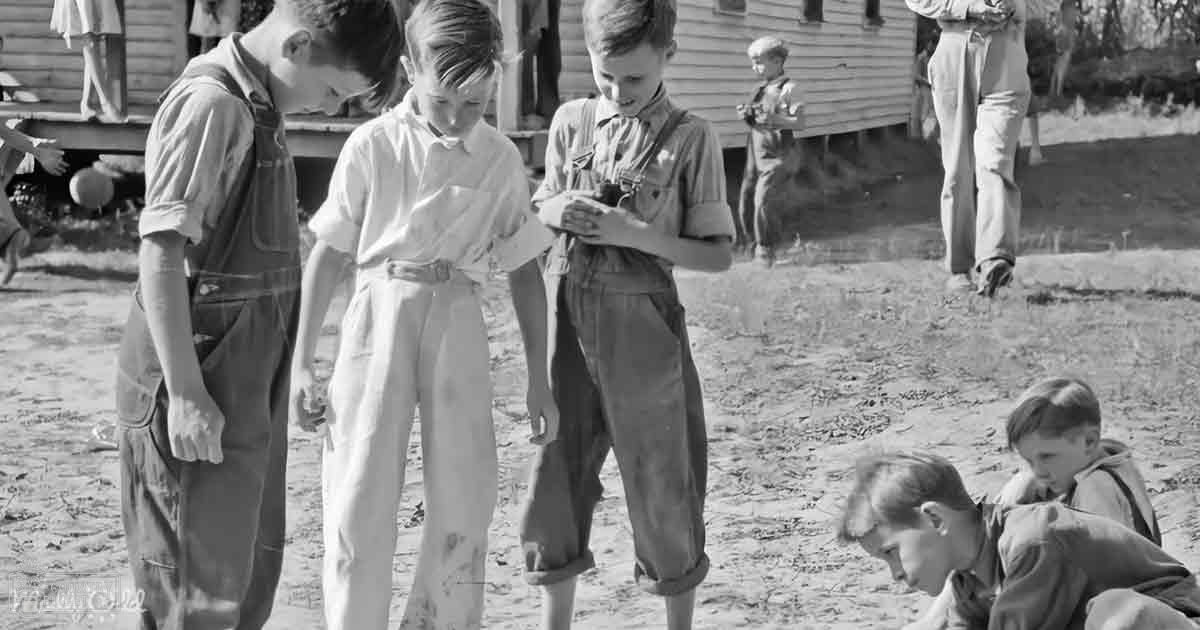 A group of children in an outdoor rural setting with a wooden house and bright daylight.