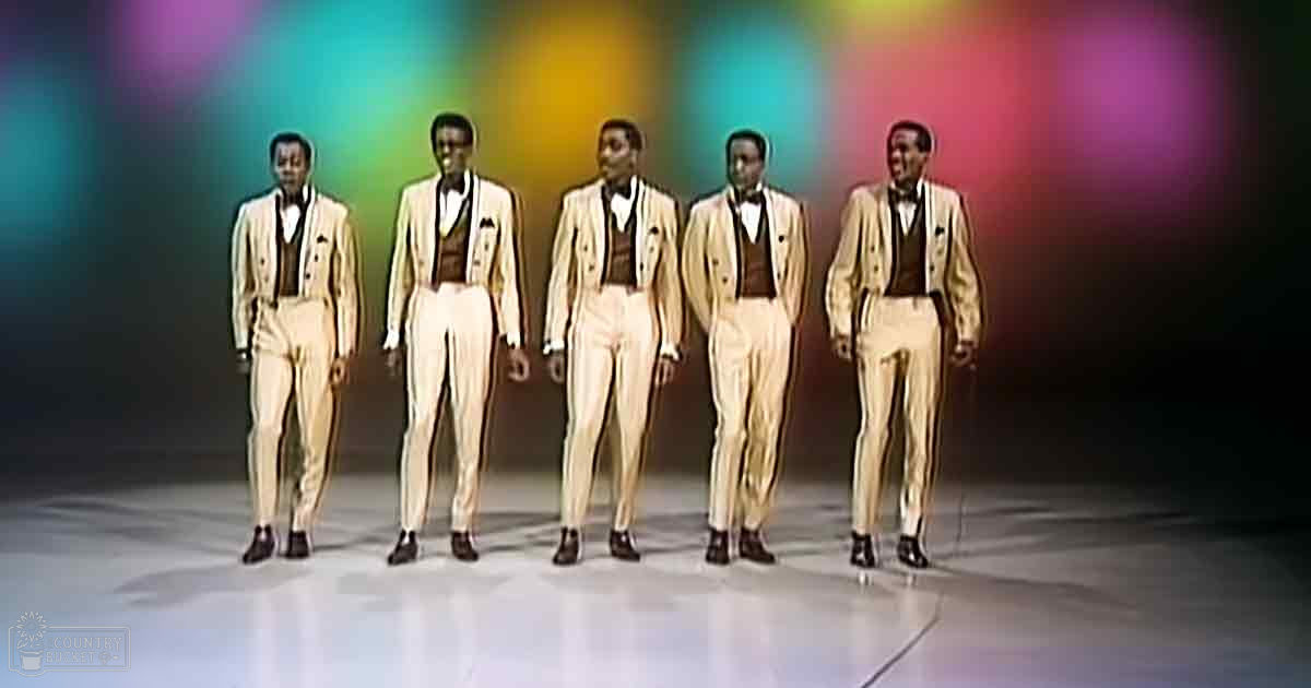 Young adult male performers in a studio setting, dressed in mid-20th century formal attire under vibrant artificial lighting.