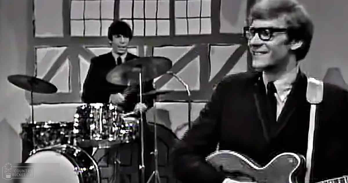 A musical performance in a studio with drum set and musicians wearing formal attire.