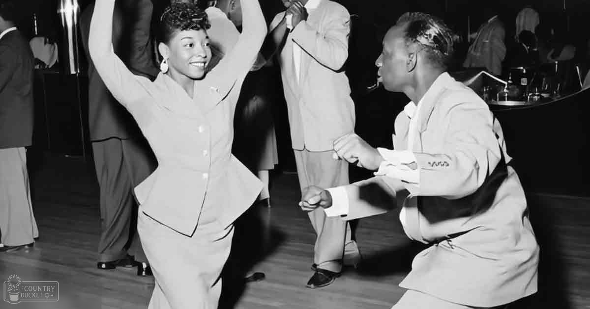 A young couple dancing in a mid-20th century social setting with wooden floors and bar area in the background.