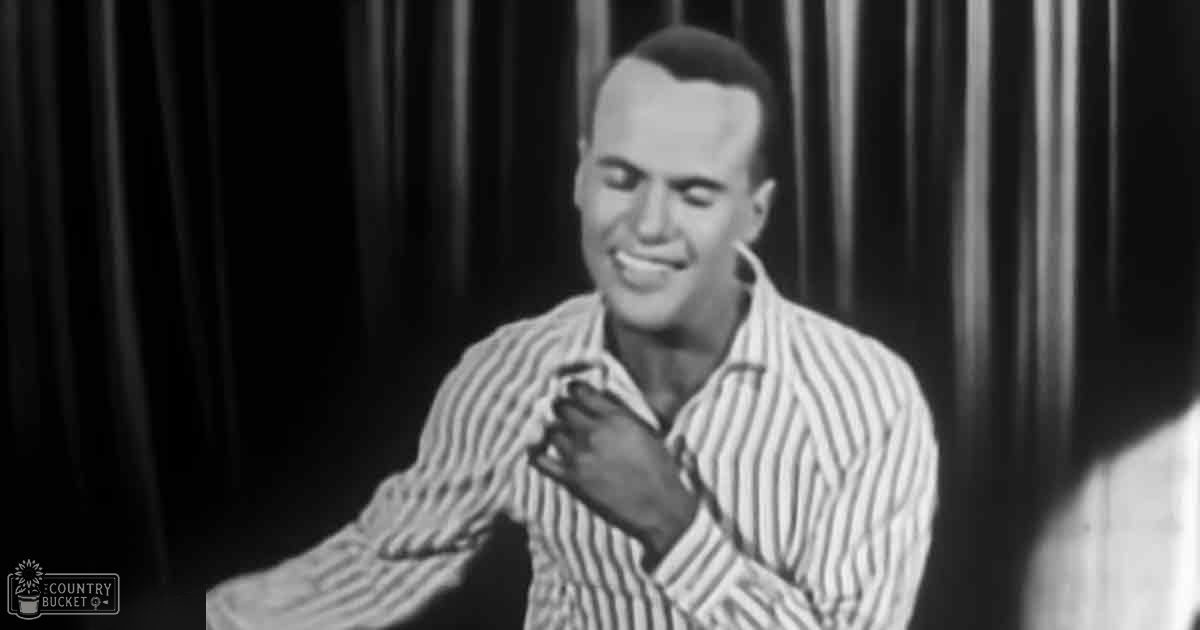 A young adult male with a striped shirt stands on an indoor stage, possibly during a performance or interview setup.