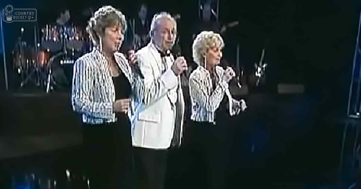 A live musical performance with performers in formal attire, possibly mid-20th century style, under stage lighting at night.