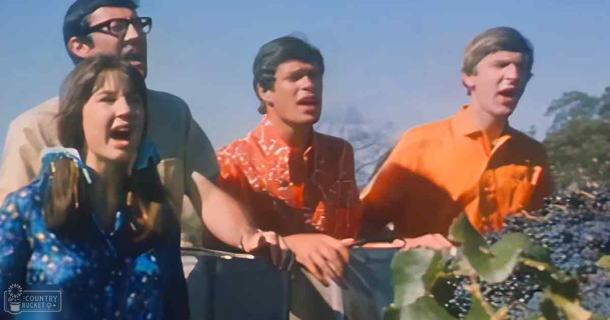 Young adults in an outdoor setting with clear skies and greenery, wearing casual clothing under bright daylight.