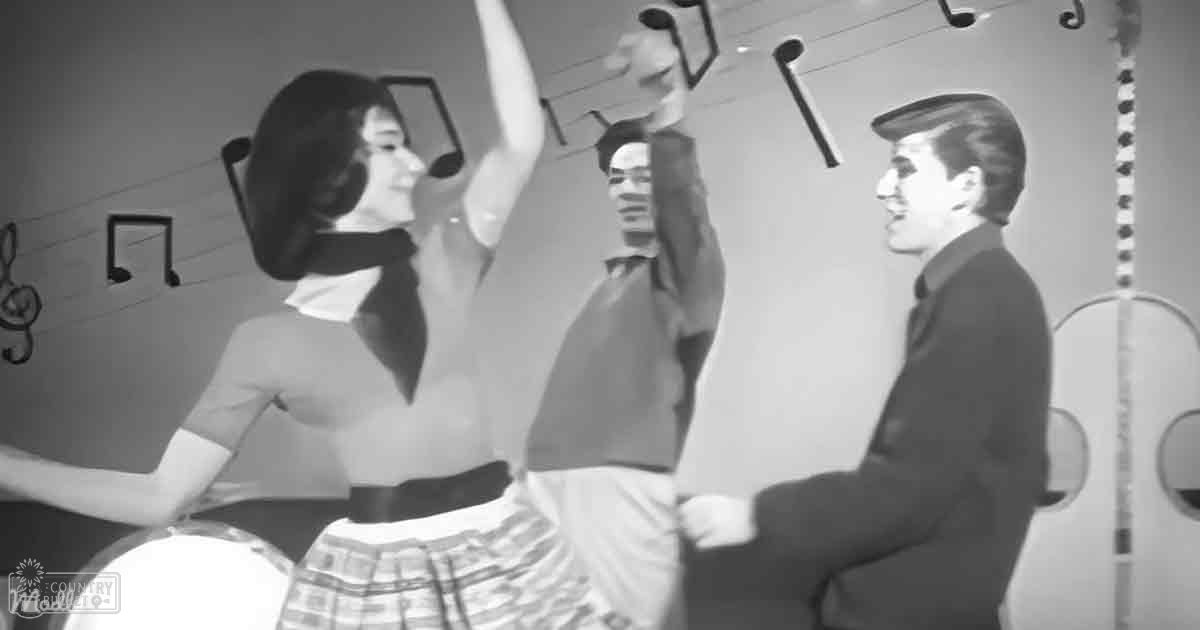 A musical performance scene with young adults performing on a stage, with a woman in a plaid skirt and scarf, and men in casual and formal attire.
